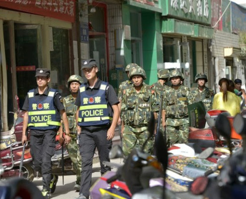 Chinese police officers and paramilitary policemen patrol a street in Kashgar city, July 23, 2014. ImagineChina